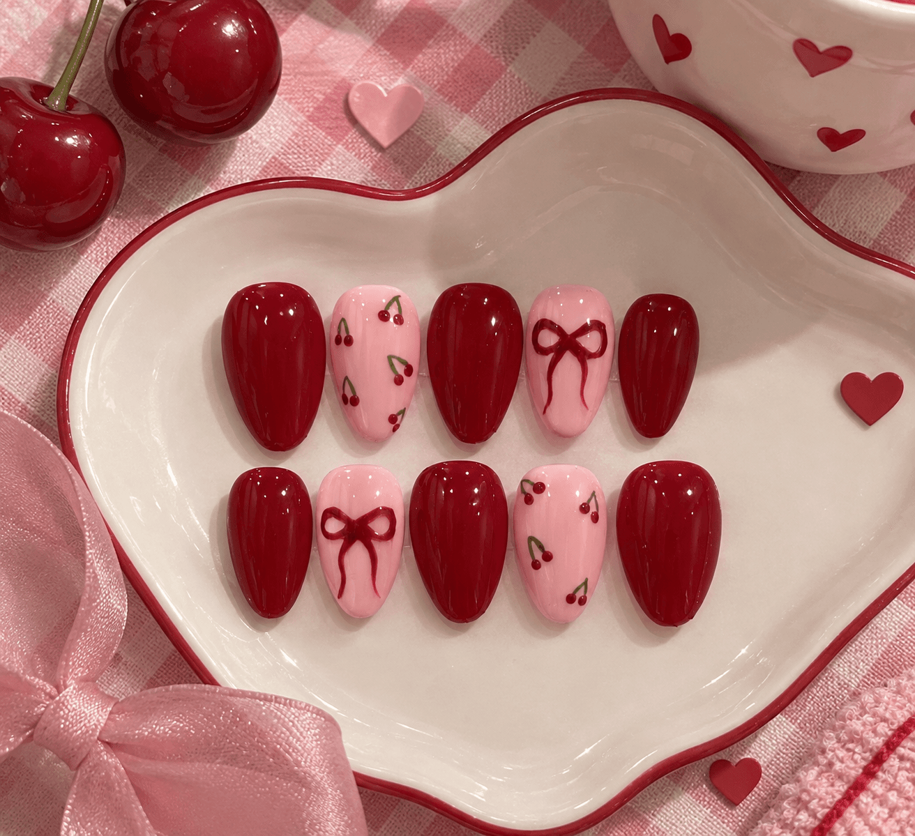 Cherry Ribbon - M size — Glossy cherry-red almond nails with pink accent nails featuring hand-painted cherries and bows.