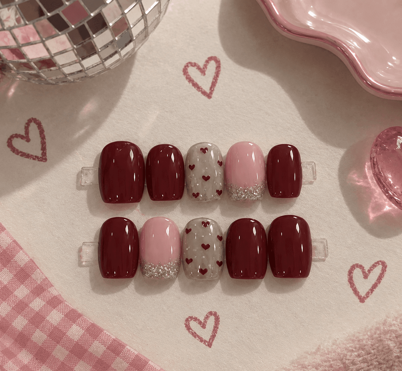 Sweetheart Wine — Short square burgundy nails with tiny red hearts and a pink glitter-tip accent.
